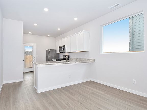 The kitchen has stainless steel appliances and plank flooring.