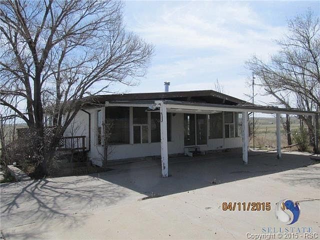 Front view of home with covered patio and shade trees.