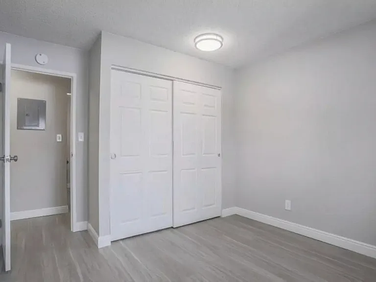 Modern, bright room with sleek light gray walls, glossy wooden flooring, and pristine white doors, creating a fresh and inviting atmosphere.
