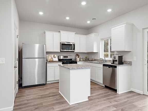 The kitchen is chef ready with plank flooring and stainless steel appliances.