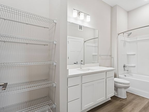 Bathroom with quartz countertops, closet, and bath/shower of an apartment unit.