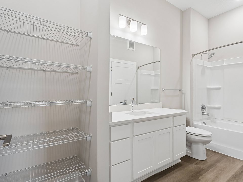 Bathroom with quartz countertops, closet, and bath/shower of an apartment unit.