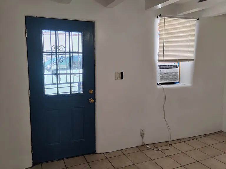 Living room with double paned steel door, tile floor and AC that cools 700 sq ft. Look how thick the adobe wall is.