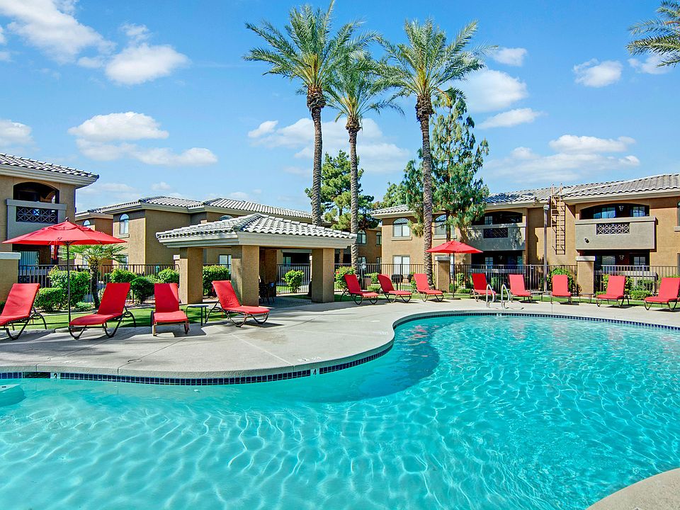 An outdoor pool with lounge chairs and palm trees
