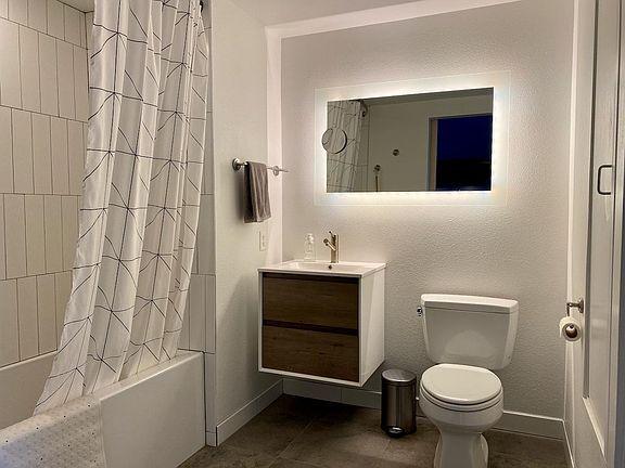 Bathroom with adjustable mirror lighting, new deep tub, sink w/ storage, as well as built-in storage closet (right).