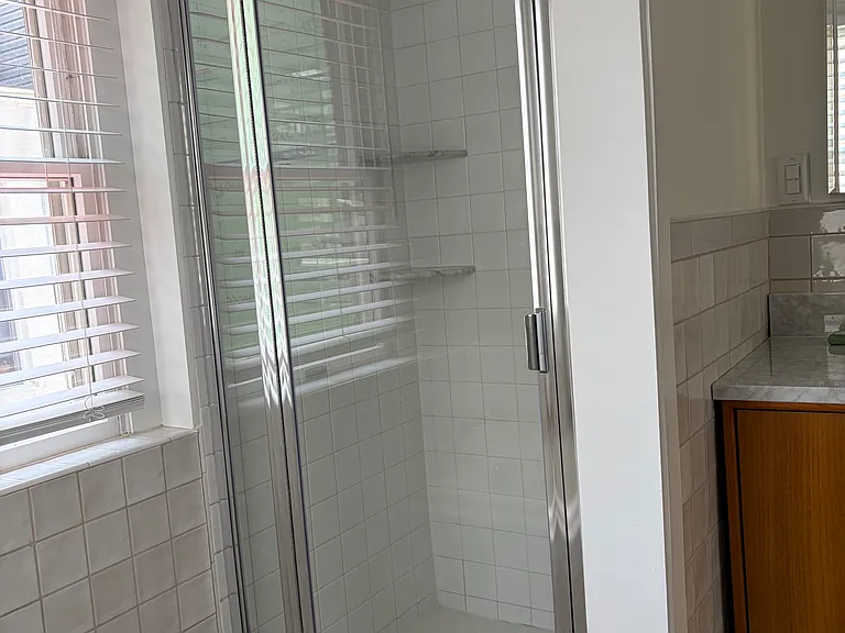 Separate shower stall with marble shelves.