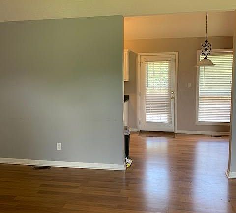 Living room with view into open dining/kitchen with back door leading onto the deck.