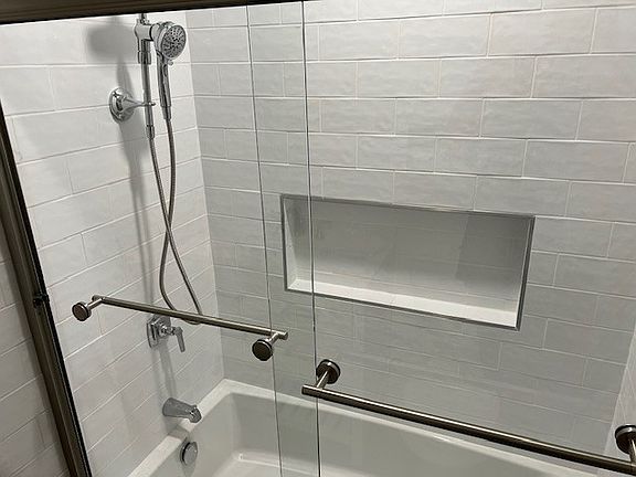 Tub and shower with glass shower door.