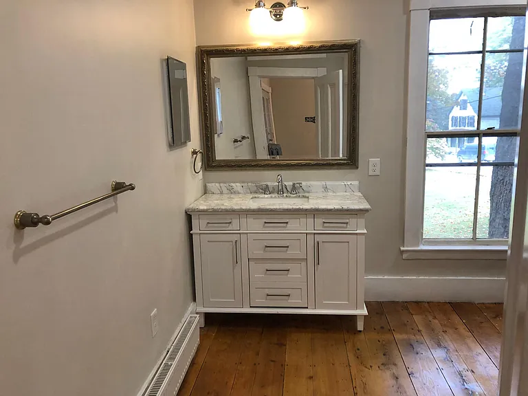 Full bathroom downstairs with marble-top vanity and pumpkin pine floors.