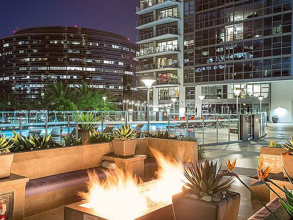Outdoor fireplace surrounded by planters and lounge seating.
