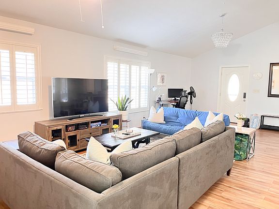 Spacious living room with natural light, plantation shutters, and ceiling fan.