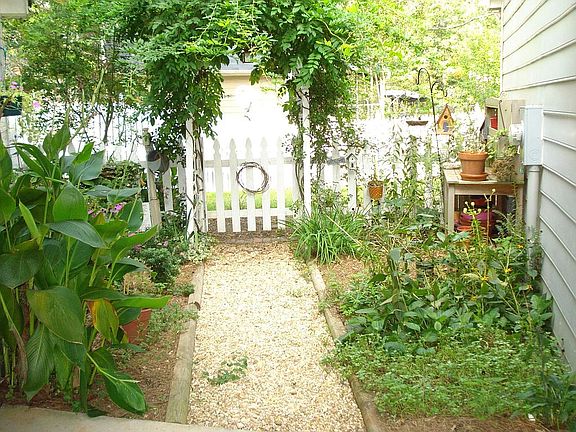 Garden area surrounds walkway leading from garage to house. 