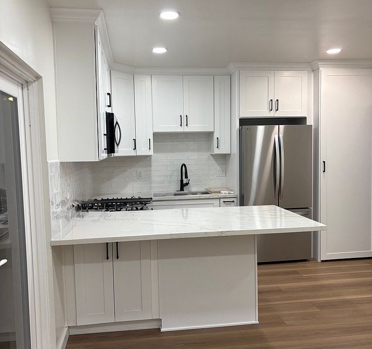 Kitchen view from living room- full gas range, microwave, sink, full refrigerator