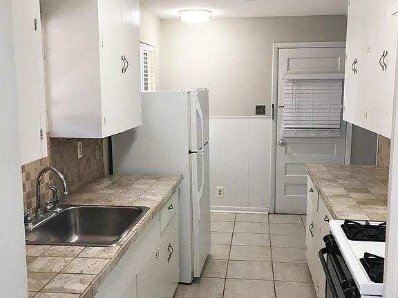 Front door leads straight to living room or kitchen on right. Kitchen with electric oven/cooktop, refrigerator, ceramic tile floor and countertops.