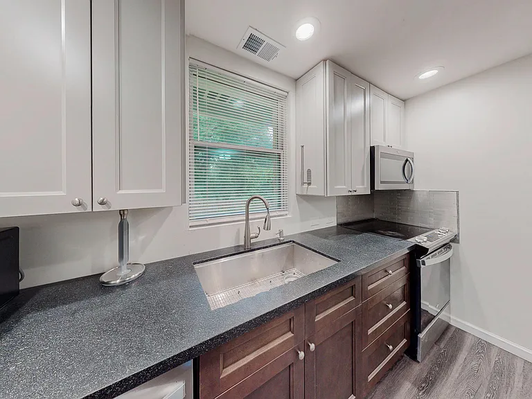 Efficient kitchen workspace with ample shaker cabinetry, wide countertops, and a sink under a window for everyday prep.