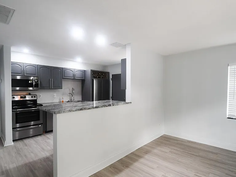Partial view of living room, kitchen with breakfast bar, looking down hallway to a brand new bedroom window. * All windows are brand new.