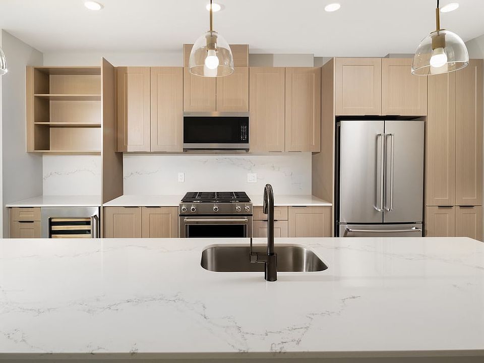 Signature Collection Kitchen with oak shaker cabinetry, marbled white quartz countertop and backsplash, and upgraded stainless steel appliances