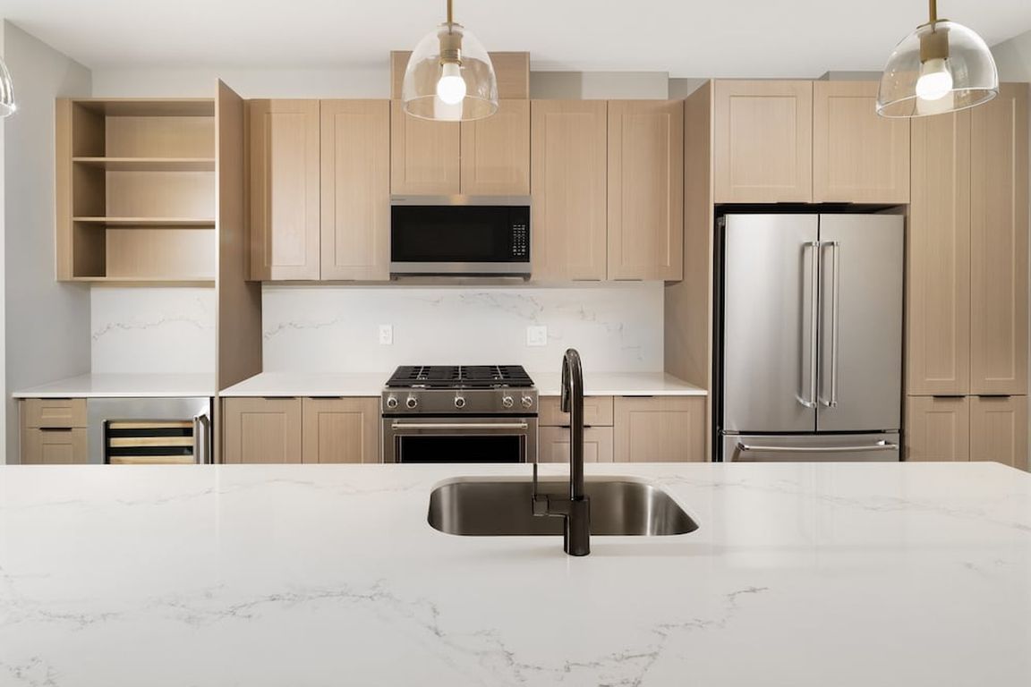 Signature Collection Kitchen with oak shaker cabinetry, marbled white quartz countertop and backsplash, and upgraded stainless steel appliances