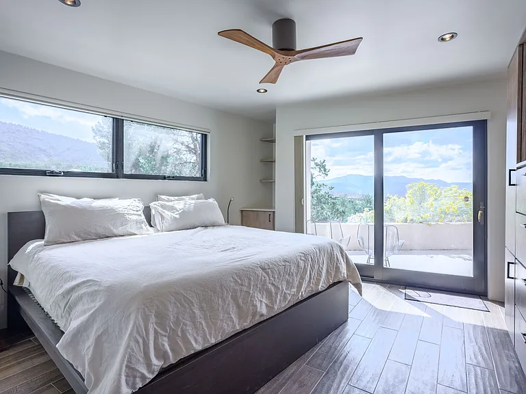 Guest room with king bed, built-in cabinets, ceiling fan, lots of light, and private patio