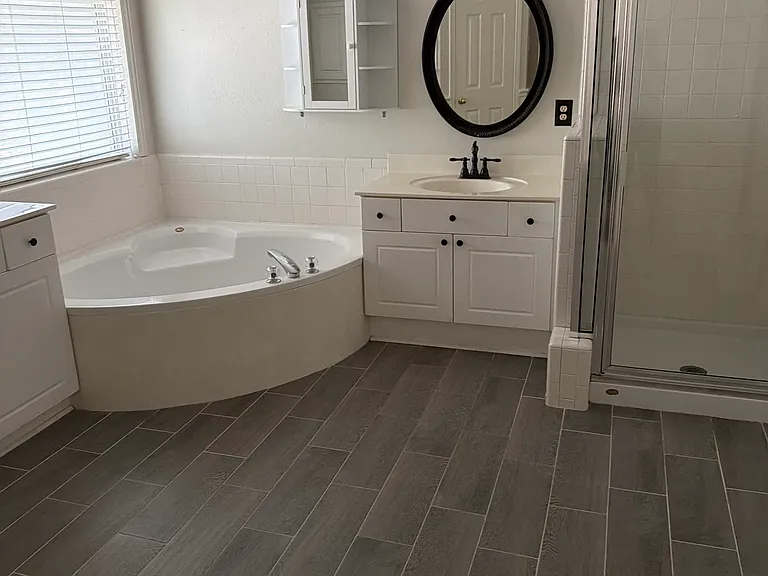 Master ensuite - enormous and lovely space to relax or get ready. Jacuzzi tub and separate shower. Floor is tile with woodgrain - lovely and easy to clean. Closet entrance is on right and toilet stall on left.