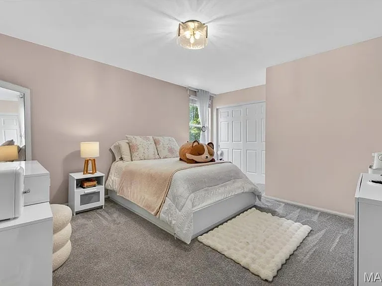 Bedroom featuring light-colored walls, gray carpeting, a window with sheer curtains, a white paneled door, and a flush-mount ceiling light fixture