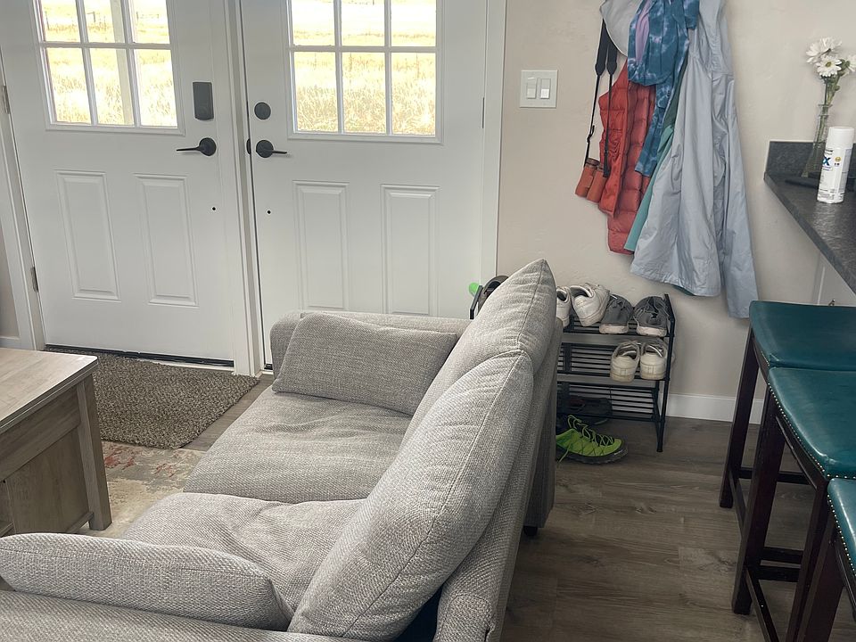 Front door with living room and bar stools at kitchen counter.
