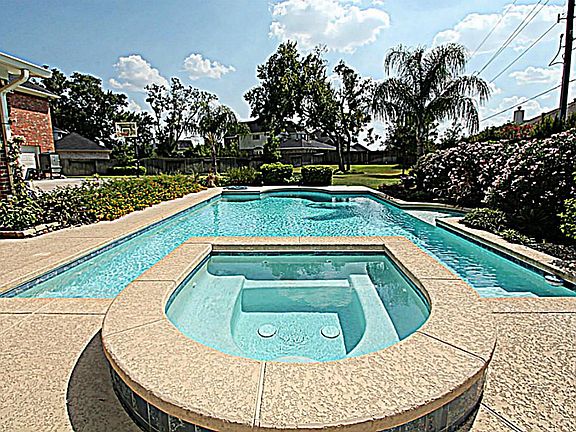 THIS BREATHTAKING HOME BOASTS A GLISTENING POOL AND SPA.