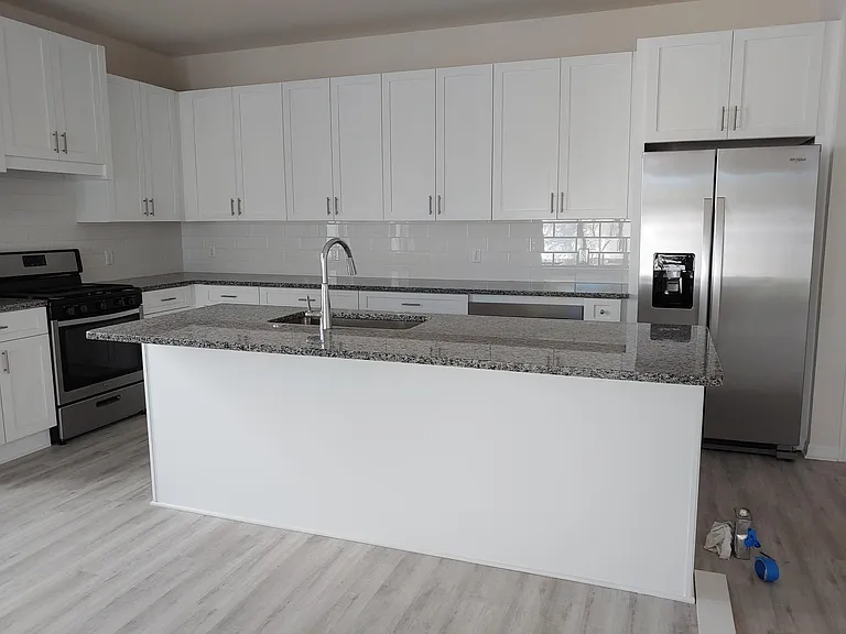 Kitchen has white wood soft close cabinets and stainless appliances, granite countertops, good sized white tiled backsplash