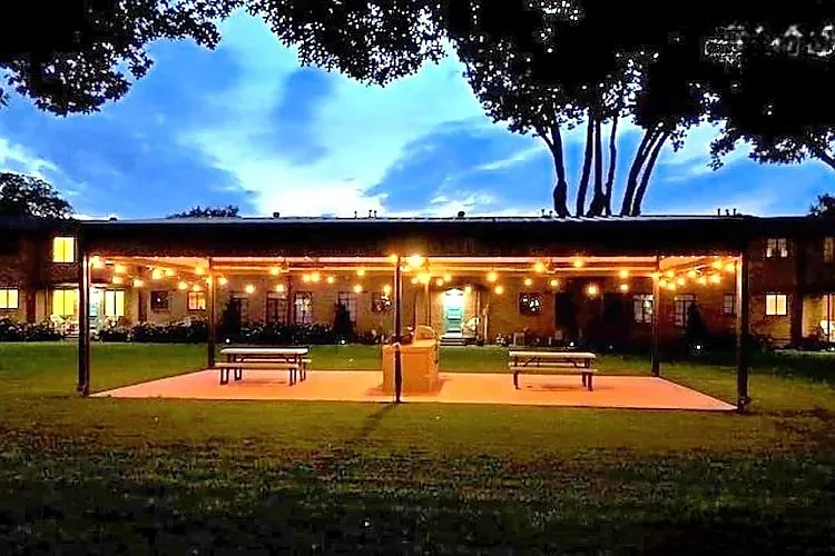 Evening courtyard view with covered picnic seating and grill area, creating a warm and inviting community space.