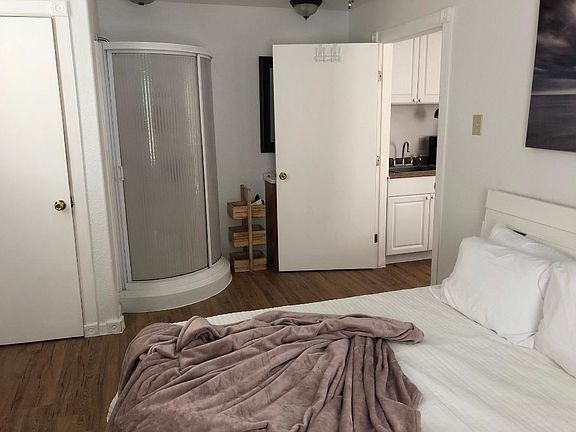 view of shower and bathroom from other side of bedroom! toilet is behind the door on the left and sink is behind the open door on the right :)