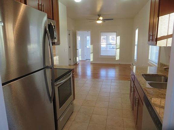 Kitchen opens to hardwood floor in living room. Lots of light and ventilation from windows and ceiling fan.