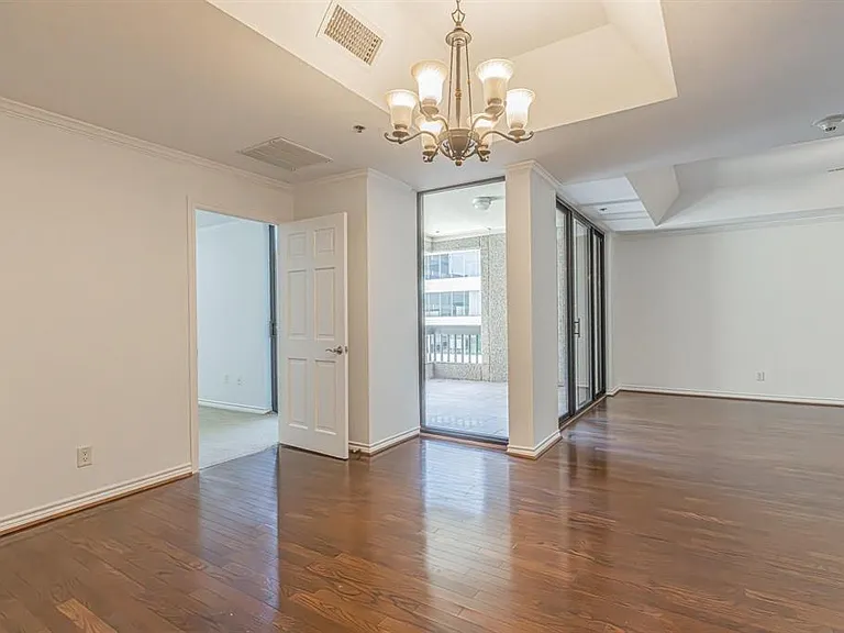 Spacious interior featuring wood-finish flooring, a tray ceiling with a chandelier, and crown molding