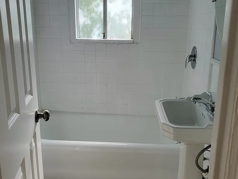 Textured floor and newly reglazed tub/tiles with toilet on other side of door