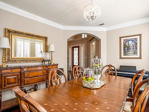 Elegant formal dining room with arched doorway, crown molding, beautiful lighting and plenty of windows that stream in natural lighting as well.