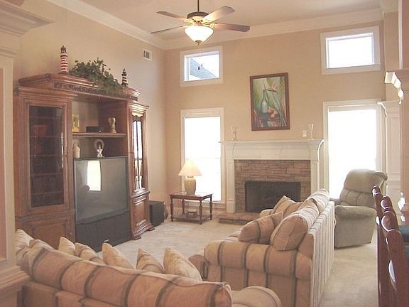 The open and bright living room features a stacked stone fireplace 