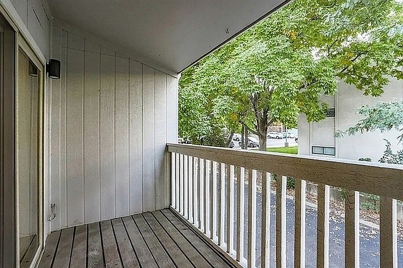 Charming apartment balcony with wooden decking and tranquil views of lush green trees, perfect for serene outdoor relaxation.