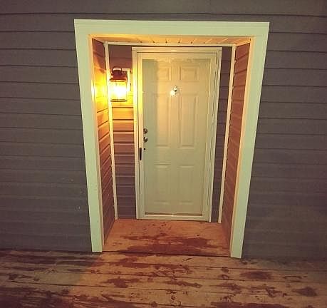 Front door at night after a rain. Large front deck, motion lights and nice, clean brand new siding