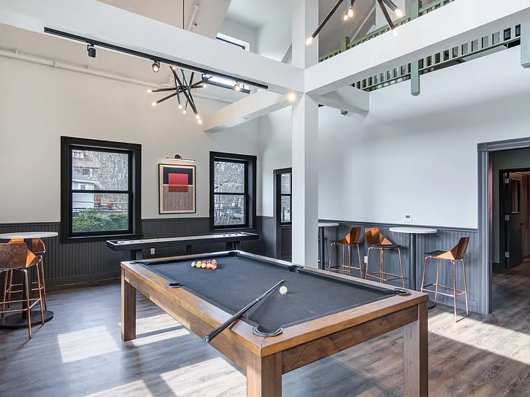 Two story game room with billiards table, shuffle board, and lounge areas