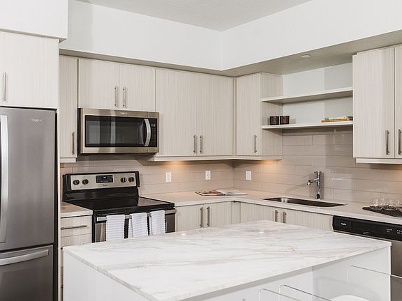 Stunning kitchens with french door stainless steel refrigerators, quartz counters, tile backsplash, and built in shelving