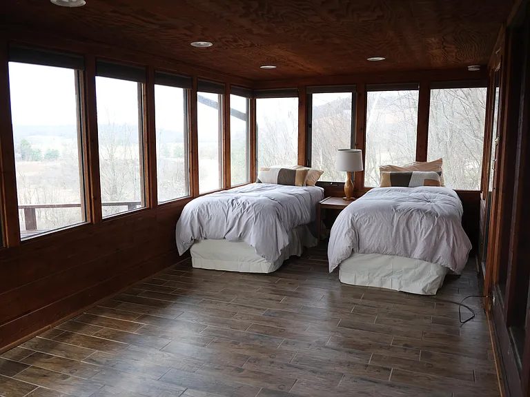 Tall windows flood this cozy retreat with natural light, offering stunning panoramic views of the surrounding landscape.