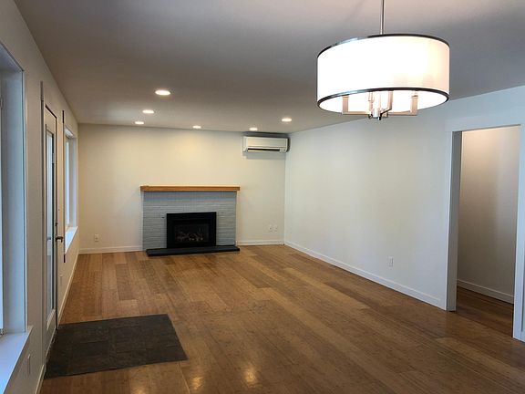 Living room (viewed from dining area) with gas fireplace and mini-split. Newly installed light fixtures.