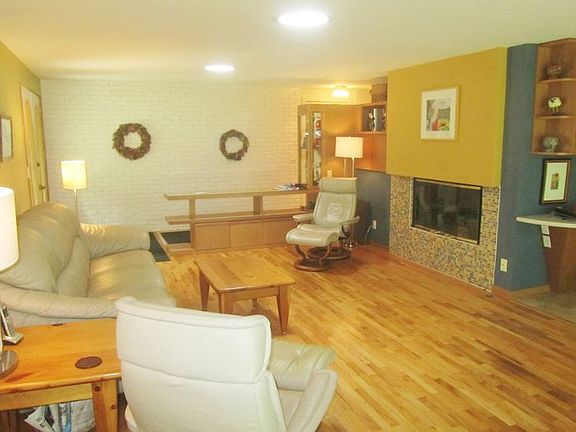 This additional view of the living room provides a view of the gas log fireplace with tile surround and built in shelving.