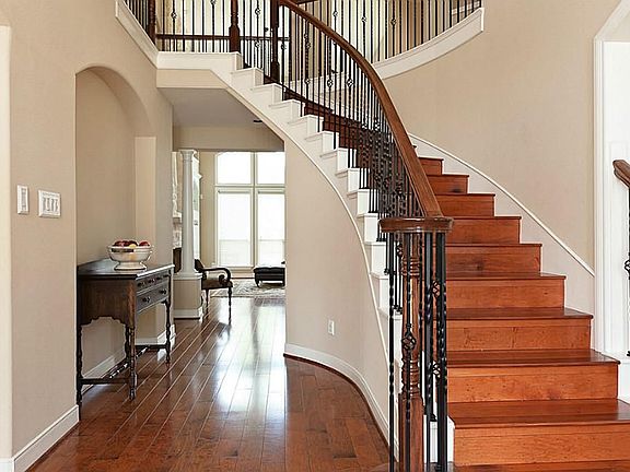 Gorgeous entry with grand staircase offering hardwood flooring and wrought iron spindles.