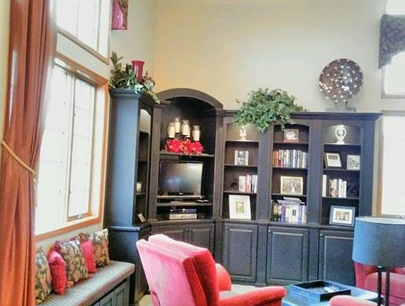 Gorgeous two story entry ushers you into a living room flooded with sunlight, custom built-in cabinetry, and a cozy window seat.