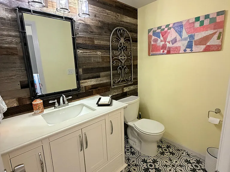 Updated bathroom on main floor. Powder room bathroom with sink & toilet, tile floor, barnwood wall