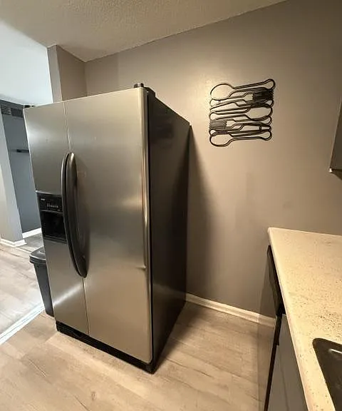 Kitchen area with a stainless-steel side-by-side refrigerator, ample counter space, and durable flooring.