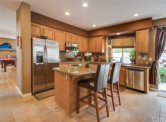 Open living concept, stainless steel appliances, granite counters, breakfast bar, travertine flooring in kitchen and family room
