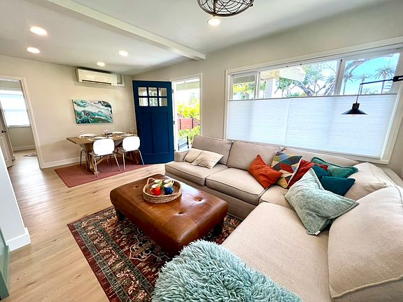 The living and dining areas flow seamlessly together, with palm tree views out every window.