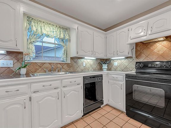 Wonderfully functional Kitchen features white wood cabinetry, under cabinet lighting, and black appliances.