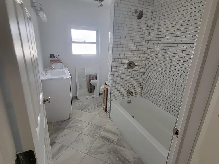 Second floor bathroom with modern tiled shower/tub and flooring.